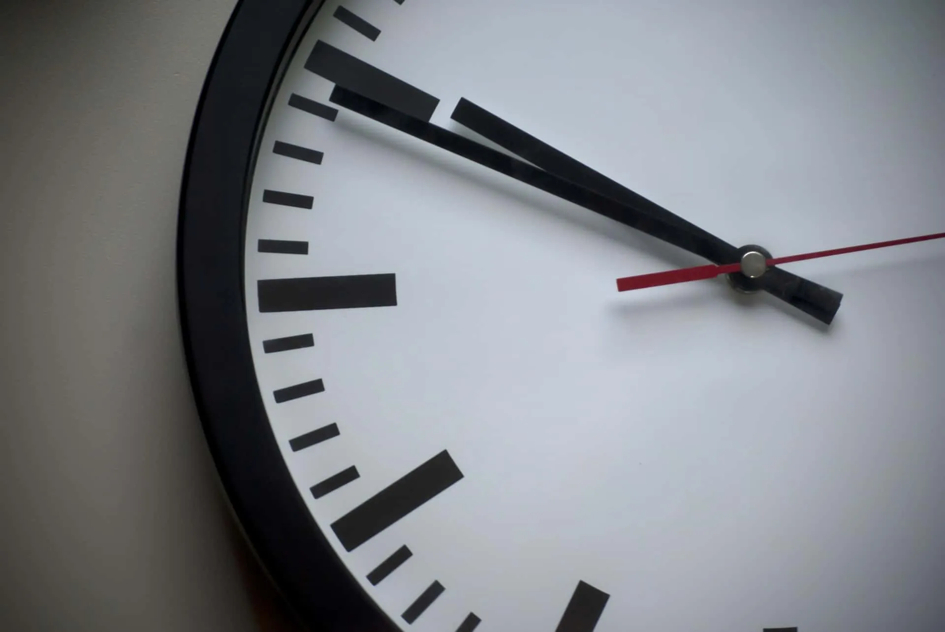 Cadran d'une horloge analogique avec aiguilles noires et trotteuse rouge indiquant 10h53